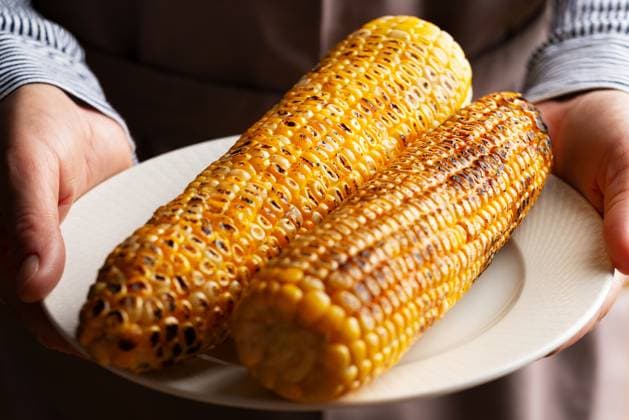 Caucasian male hands holds plate with grilled sweetcorn Caucasian male hands holds plate with grilled sweetcorn Copyright: xZoonar.com DmytroxMykhailovx 21168315