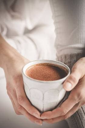 Creative Highlights Symbolbilder A person holding a mug with a delicious and frothy hot chocolate in a cozy, warm setting, capturing the essence of comfort Model Released JoannaFufal_ID20669_610229_005 Copyright: xJoannaxFufalx