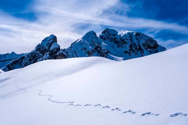 Snow-covered slopes of alpine Dolomite landscape around Giau pass with a hare trail in winter, the snow-covered summits of Torre Dusso and Mt. Cernera in the distance. Cortina d˜Ampezzo Veneto Italy FB_2024_1063