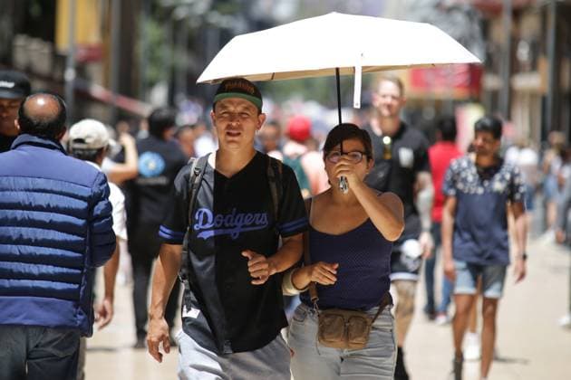 Mexiko, Rekordtemperaturen in Teilen des Landes (240417) -- MEXICO CITY, April 17, 2024 -- Two pedestrians shield themselves from the sun with an umbrella in Mexico City, Mexico, on April 16, 2024. (Photo by Xinhua) MEXICO-MEXICO CITY-HEAT WAVE FranciscoxCanedo 