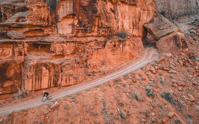 Creative Highlights Symbolbilder Man rides bike down narrow dirt road on cliff face, Moab, Utah Moab, Utah, United States CR_SSNF240416E-1380705-01 ,model released, Symbolfoto