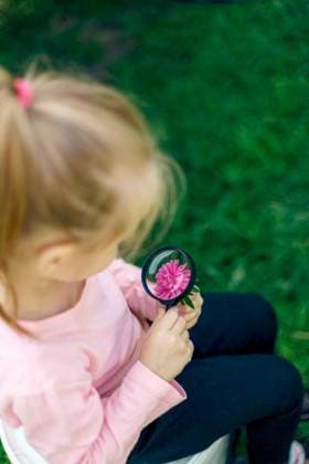 IMAGO Creative, Sommer, Sommertage im Garten A child examines a flower under a magnifying glass Chi?in?u, Chisinau, Moldova CR_WCIK24042116-1390972-01 ,model released, Symbolfoto