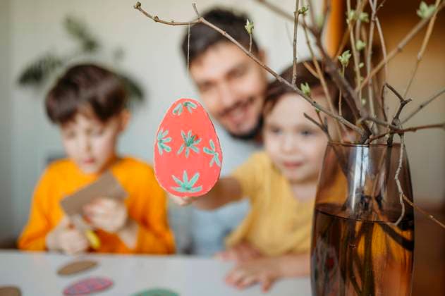 Cardboard Easter egg hanging on twig with family in background model released, Symbolfoto property released, ANAF02761