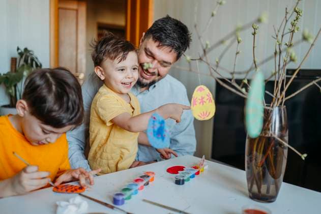 Boy painting near brother touching cardboard Easter egg hanging on twig with father at home model released, Symbolfoto property released, ANAF02769