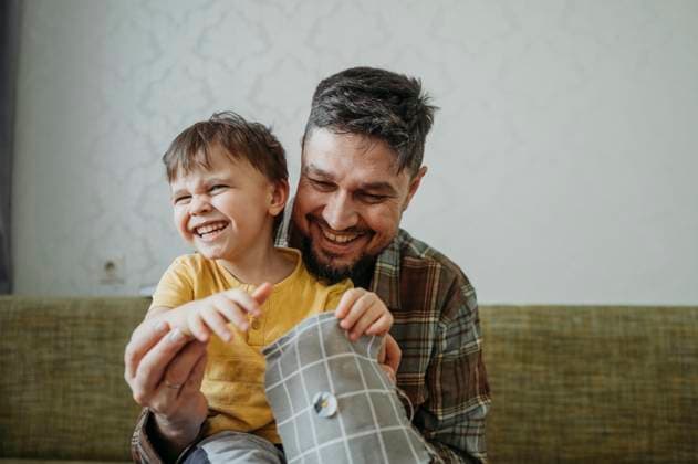Creative Highlights Symbolbilder Happy father teaching son to sew button on gray colored cloth at home model released, Symbolfoto property released, ANAF02793