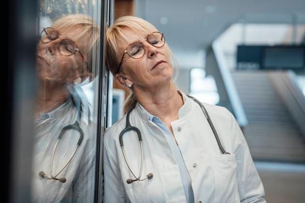 Mature doctor leaning with eyes closed on vending machine in hospital model released, Symbolfoto property released, JOSEF23962
