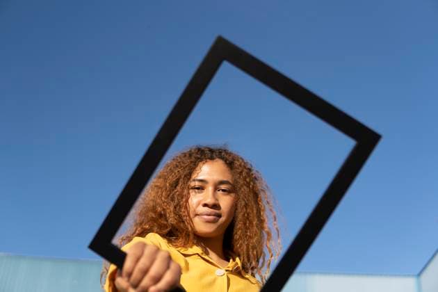 Creative Highlights Symbolbilder Confident young woman looking through picture frame under clear blue sky model released, Symbolfoto, MGRF01187