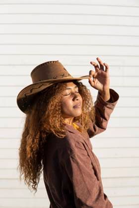 Creative Highlights Symbolbilder Young woman with eyes closed wearing jacket and cowboy hat on sunny day model released, Symbolfoto, MGRF01227