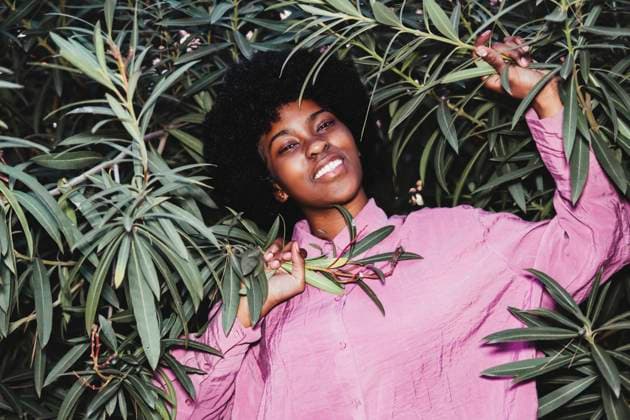 Creative Highlights Symbolbilder Smiling teenage girl wearing pink shirt and holding plant leaves model released, Symbolfoto, PBTF00505