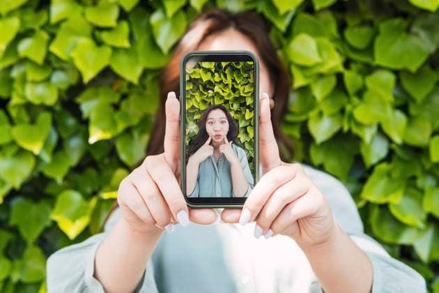 Creative Highlights Symbolbilder Woman showing picture on smart phone near hedge model released, Symbolfoto property released, PNAF06140