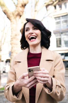 Creative Highlights Symbolbilder Happy mature businesswoman wearing overcoat using smart phone model released, Symbolfoto, AMWF02261