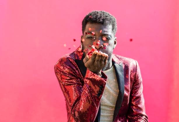 Creative Highlights Symbolbilder Young non-binary person blowing confetti against pink background model released, Symbolfoto property released, JCCMF11667