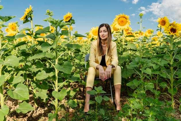 Creative Highlights Symbolbilder Confident businesswoman sitting on chair amidst sunflowers in field model released, Symbolfoto, OSF02491