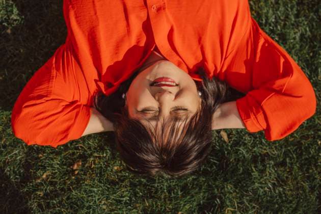 IMAGO Creative, Frühling, Licht und Sonne Smiling mature woman with hands behind head lying on grass in back yard model released, Symbolfoto, VSNF01847