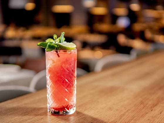 Red pink cocktail with lime and mint in restaurant Red non-alcohol cocktail with crushed ice in glass on wooden bar counter in restaurant interior. Gin alcohol cocktail decorated lime and mint. Pink cold alcoholic cocktail in bar or nightclub background. Copy space Copyright: xZoonar.com OlgaxSergeevax 21392716