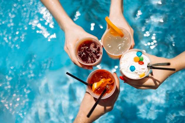 Close-up of female and male hands holding glasses with iced cocktails and clinking them. Friends make festive toast with delicious drinks against background of clear blue pool water. Close-up of female and male hands holding glasses with iced cocktails and clinking them. Friends make festive toast with delicious drinks against background of clear blue pool water. Party, vacation. Copyright: xZoonar.com DashaxPetrenkox 21475956