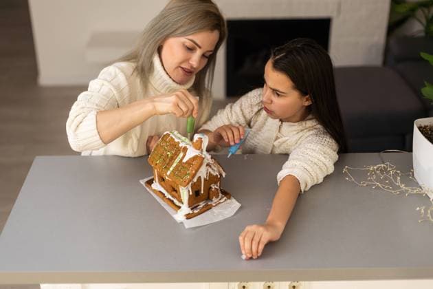 Mother and daughter making gingerbread cookies house, decorating at home, Christmas concept Mother and daughter making gingerbread cookies house, decorating at home, Christmas concept. Copyright: xsinenkiy RECORD DATE NOT STATED