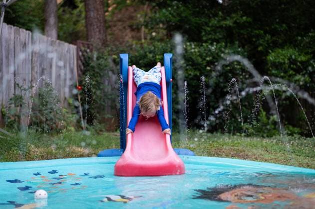 IMAGO Creative, Sommer, Sommertage im Garten Young boy slides headfirst down toddler slide into splah pad. Atlanta, Georgia, United States R_PJUI240426-1406671-01 ,model released, Symbolfoto