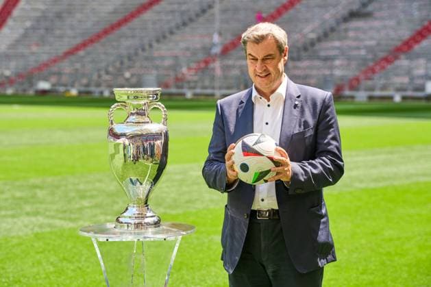 Munich, Bavaria, Germany - 13 May 2024: Prime Minister Dr. Markus Söder (CSU) on the soccer pitch at the Allianz Arena in Munich. He stands next to the Henri Delaunay Cup of the UEFA EURO 2024 and holds an original Adidas soccer of the European Football Championship
