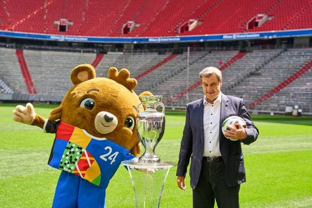 Munich, Bavaria, Germany - 13 May 2024: Prime Minister Dr. Markus Söder (CSU) on the soccer pitch at the Allianz Arena in Munich. He stands next to the Henri Delaunay Cup of the UEFA EURO 2024 and holds an original Adidas soccer of the European Football Championship