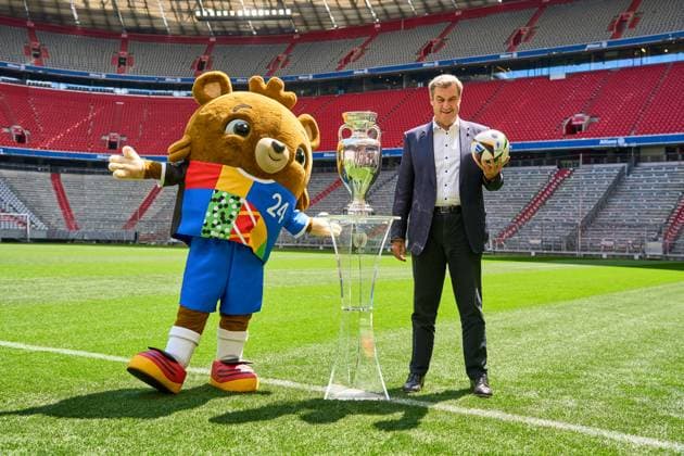 Munich, Bavaria, Germany - 13 May 2024: Prime Minister Dr. Markus Söder (CSU) on the soccer pitch at the Allianz Arena in Munich. He stands next to the Henri Delaunay Cup of the UEFA EURO 2024 and holds an original Adidas soccer of the European Football Championship