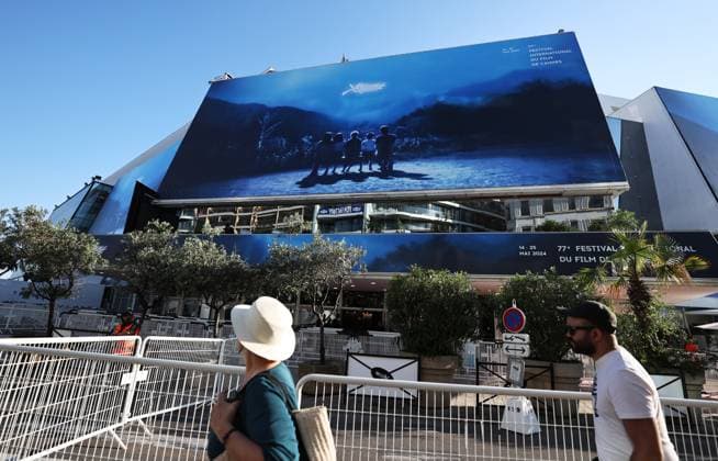 (240514) -- CANNES, May 14, 2024 -- People walk past a huge poster of the 77th edition of the Cannes Film Festival outside the Palais du Festival in Cannes, southern France, May 13, 2024. This year s festival runs from May 14 to 25. ) FRANCE-CANNES-FILM FESTIVAL-HUGE POSTER GaoxJing 