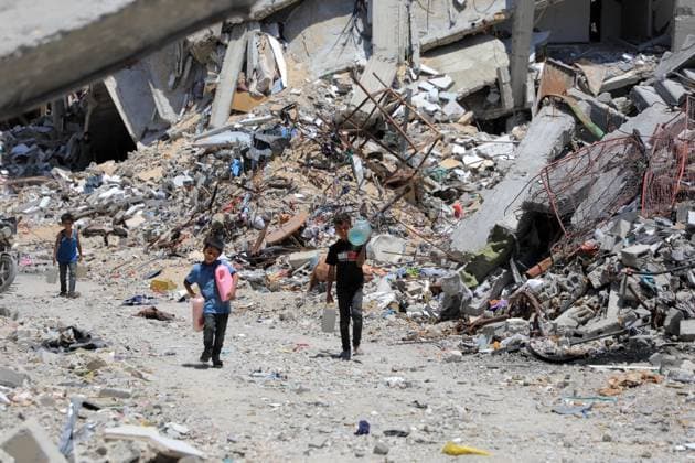 Bilder des Jahres 2024, News 05 Mai News Themen der Woche KW20 News Bilder des Tages (240513) -- GAZA, May 13, 2024 -- Children carrying containers of water walk past destroyed buildings in the southern Gaza Strip city of Khan Younis, on May 13, 2024. The Palestinian death toll from the ongoing Israeli attacks on the Gaza Strip has risen to 35,091, health authorities in the Palestinian enclave said in a press statement on Monday. (Photo by Xinhua) MIDEAST-GAZA-KHAN YOUNIS-DESTROYED BUILDINGS RizekxAbdeljawad 
