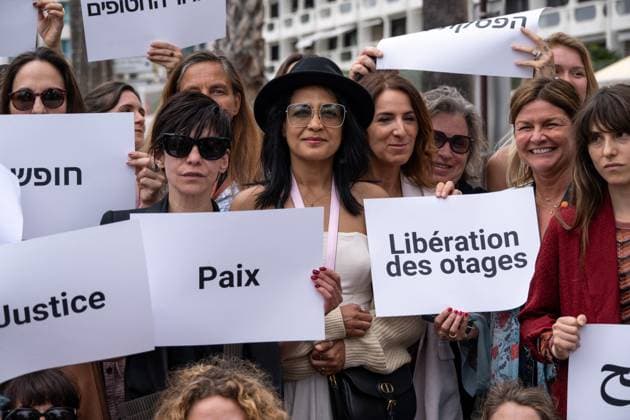 Cannes - Guerrieres De La Paix Flash Mob Action for Gaza and Israel Moroccan Belgian actress Loubna Azabal (first from L) and producer Lamia Chraibi (2nd from L) and other women from ?Women warriors of peace? carry messages in French, Arabic, Hebrew and English stating ?Peace?, ?Cease Fire?, Release the Hostages?, demonstrate on the ?Croisette? in Cannes, to draw attention to the situation in Gaza and Israel, around the 77th Cannes Film Festival, in Cannes, France, on May 20, 2024. Photo by Ammar Abd Rabbo ABACAPRESS.COM Cannes France  Copyright: xABACAx