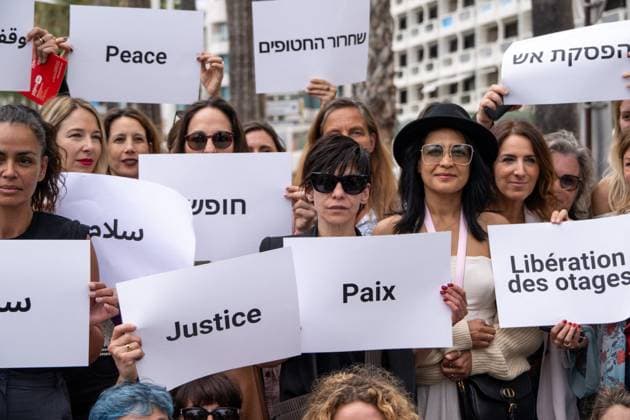 Cannes - Guerrieres De La Paix Flash Mob Action for Gaza and Israel Moroccan Belgian actress Loubna Azabal (first from L) and producer Lamia Chraibi (2nd from L) and other women from ?Women warriors of peace? carry messages in French, Arabic, Hebrew and English stating ?Peace?, ?Cease Fire?, Release the Hostages?, demonstrate on the ?Croisette? in Cannes, to draw attention to the situation in Gaza and Israel, around the 77th Cannes Film Festival, in Cannes, France, on May 20, 2024. Photo by Ammar Abd Rabbo ABACAPRESS.COM Cannes France  Copyright: xABACAx