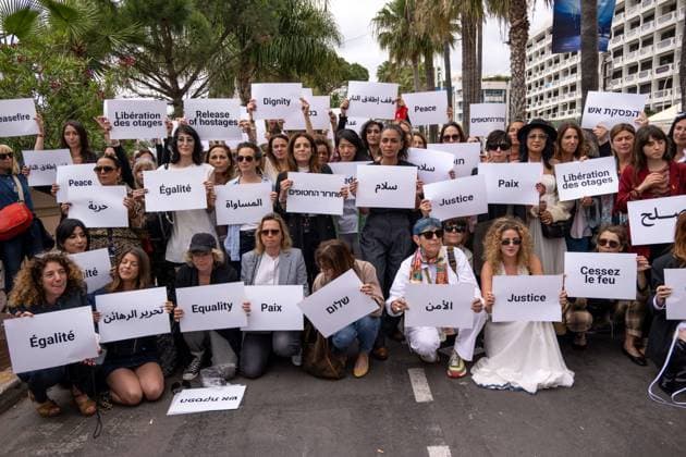 Cannes - Guerrieres De La Paix Flash Mob Action for Gaza and Israel Moroccan Belgian actress Loubna Azabal (first from L) and producer Lamia Chraibi (2nd from L) and other women from ?Women warriors of peace? carry messages in French, Arabic, Hebrew and English stating ?Peace?, ?Cease Fire?, Release the Hostages?, demonstrate on the ?Croisette? in Cannes, to draw attention to the situation in Gaza and Israel, around the 77th Cannes Film Festival, in Cannes, France, on May 20, 2024. Photo by Ammar Abd Rabbo ABACAPRESS.COM Cannes France  Copyright: xABACAx