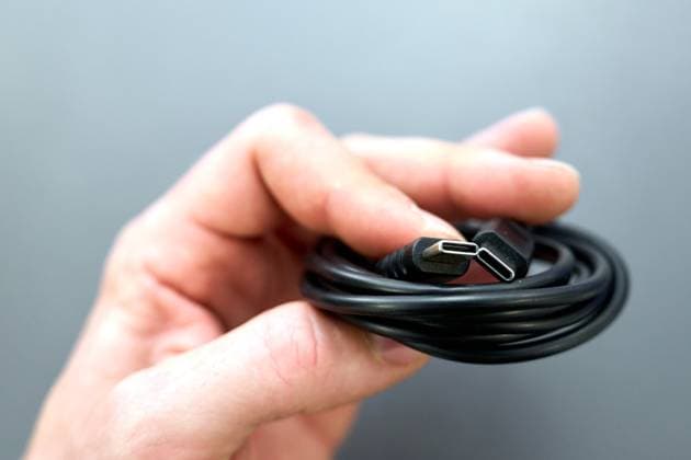Augsburg, Bavaria, Germany - 18 May 2024: Hand holding a charging and data cable with USB-C plug *** Hand hält ein Lade- und Datenkabel mit USB-C Stecker