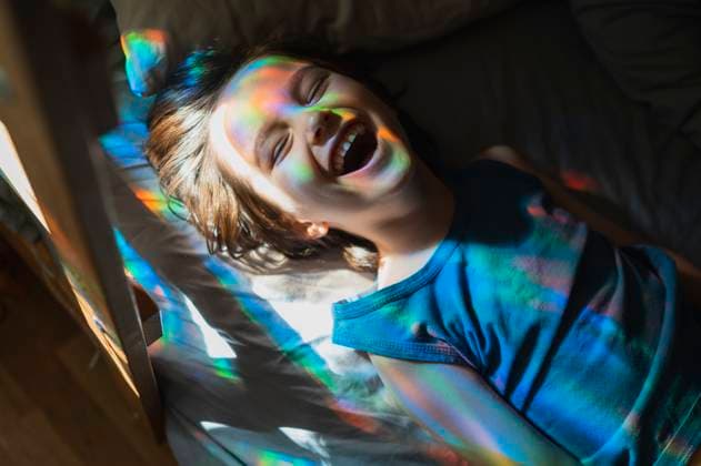 Creative Highlights Symbolbilder Laughing boy with eyes closed lying on bed at home model released, Symbolfoto property released, ANAF02887