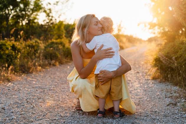 Creative Highlights Symbolbilder Mother embracing son on footpath at sunset model released, Symbolfoto, NDEF01742