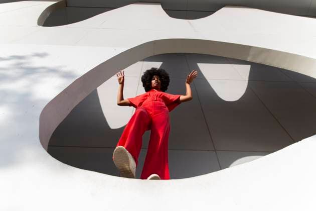 Creative Highlights Symbolbilder Mature woman with Afro hairstyle in red jumpsuit standing on white wall model released, Symbolfoto, PCLF01075