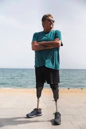 Creative Highlights Symbolbilder Disabled senior man with prosthetic legs standing with arms crossed at beach on sunny day model released, Symbolfoto, PCLF01180