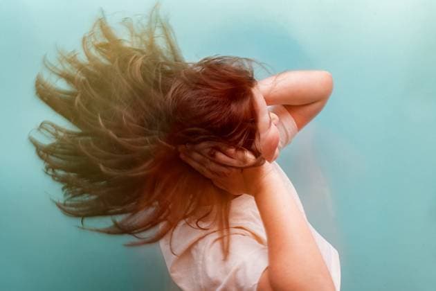 Creative Highlights Symbolbilder A distressed young woman holds her head, her hair flowing, set against a serene teal background, illustrating symptoms of hypoglycemia Model Released HodeiUnzueta_ID21613_634448_027 Copyright: xHodeixUnzuetax