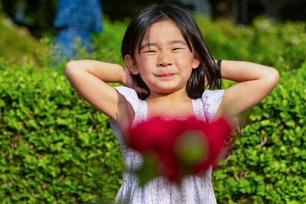 Creative Highlights Symbolbilder A young Asian girl stands in a lush green park during a family vacation in Europe, smiling with her hands behind her head Model Released JuanAizpuru_ID21367_628903_027 Copyright: xJuanxAizpurux