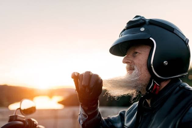 Creative Highlights Symbolbilder Side view of elderly male motorcyclist in a helmet looks away while savoring the freedom of a scenic ride at sunset, expressing adventure and serene retirement. Model Released SergioVictorVega_ID21276_626571_023 Copyright: xSergioxVictorxVegax