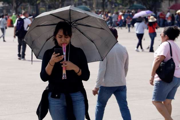 A woman enjoys a ice pop while walking using an umbrella to cover herself from the sun at the historic center of Mexico due high temperatures that hits Mexico. Mexico City Mexico - ZUMAe321 20240528_zia_e321_005 Copyright: xLuisxBarronx