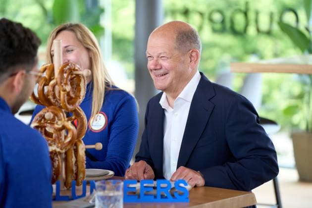 Munich, Bavaria, Germany - June 3, 2024: Federal Chancellor Olaf Scholz visits the Olympic Park in Munich, Bavaria on the occasion of UEFA EURO 2024. The Chancellor talks to helpers around the European Football Championship at a table with Bavarian pretzels