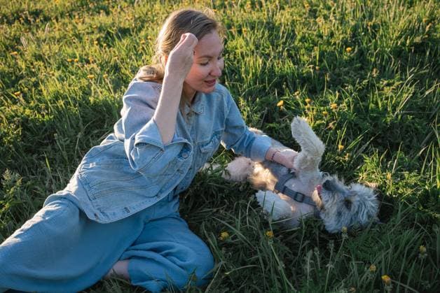 Creative Highlights Symbolbilder young woman with a dog without a breed is lying on the grass Espoo, Uusimaa, Finland R_PJJZ240610-1454270-01 ,model released, Symbolfoto