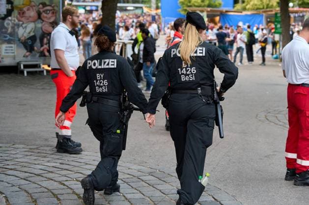 Munich, Bavaria, Germany - June 14, 2024: Two female police officers with weapon and baton in action at the fan mile for UEFA EURO 2024, the European Football Championship, at the match between Germany and Scotland. You can see paramedics on standby at the soccer match