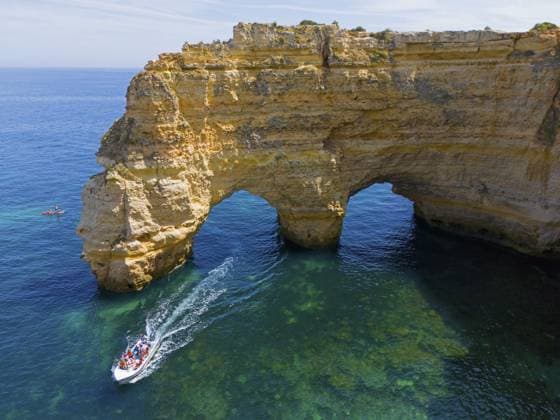A large boat passes under natural arches made of rocks in crystal clear water on the coast, aerial view, Praia da Marinha, double rock arch, Lagoa, Rocky Algarve, Algarve, Portugal, Europe *** a Large Boat Passes Under Natural Arches Made of Rocks in Crystal Clear Water ON The coast, Aerial view, Praia as Marinha, Double Rock arch, Lagoa, Rocky Algarve, Algarve, Portugal, Europe Copyright: imageBROKER FraukexScholz ibxsco10780226.jpg