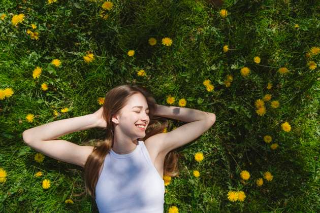 IMAGO Creative, Frühling, Licht und Sonne Happy teenage girl lying on yellow dandelions in park model released, Symbolfoto, IHF02028