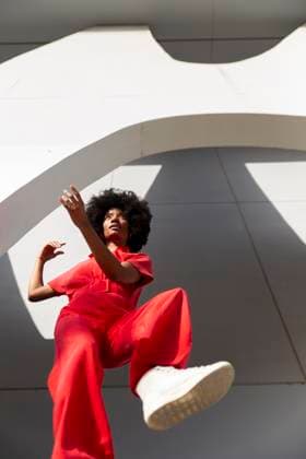 Creative Highlights Symbolbilder Mature woman wearing red jumpsuit and standing under modern building model released, Symbolfoto, PCLF01107