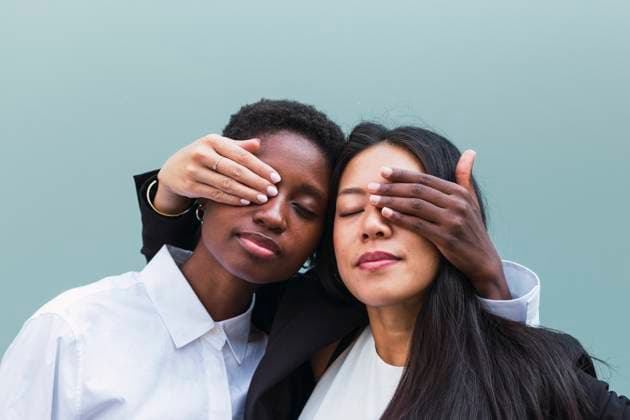 Creative Highlights Symbolbilder Multiracial businesswomen covering each other s eyes in front of blue wall model released, Symbolfoto, PNAF06280