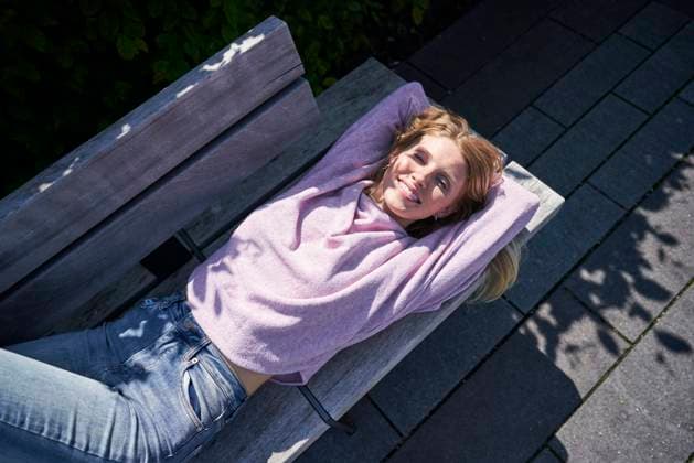 Creative Highlights Symbolbilder Happy woman wearing purple sweater lying down on bench model released, Symbolfoto, PNEF03153