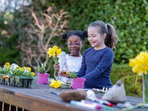 Girl friends (6-7) potting plants in back yard model released Copyright: xCulturaxCreativex