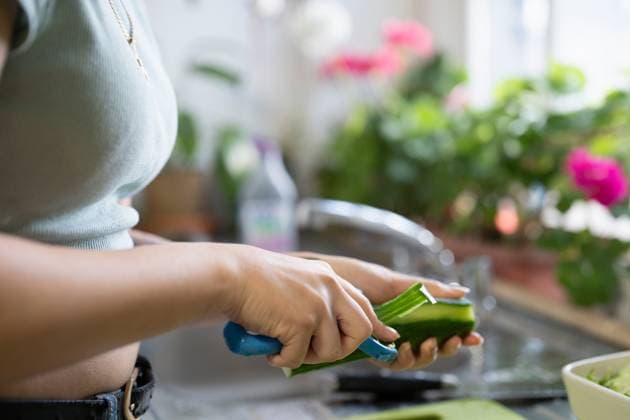 Close-up of young woman peeling vegetables in kitchen model released Copyright: xCulturaxCreativex