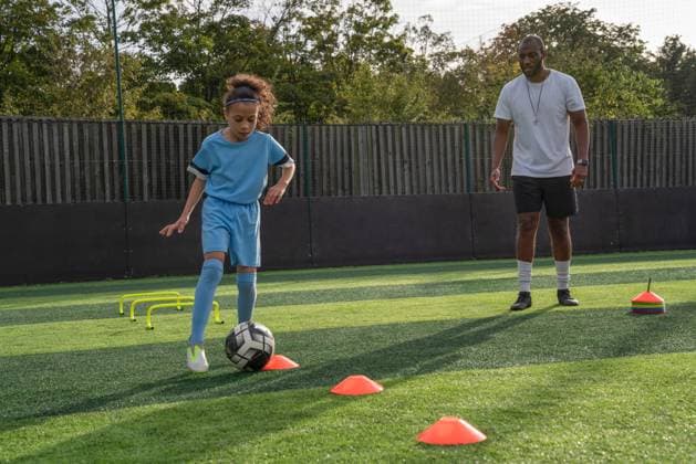 Coach watching girl (6-7) practicing on soccer field model released Copyright: xCulturaxCreativex